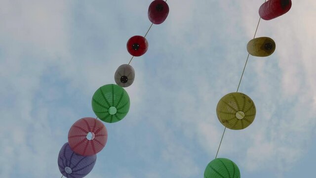Chinese lamps shot against the blue sky and dangling in the wind between houses in Chinatown, London.