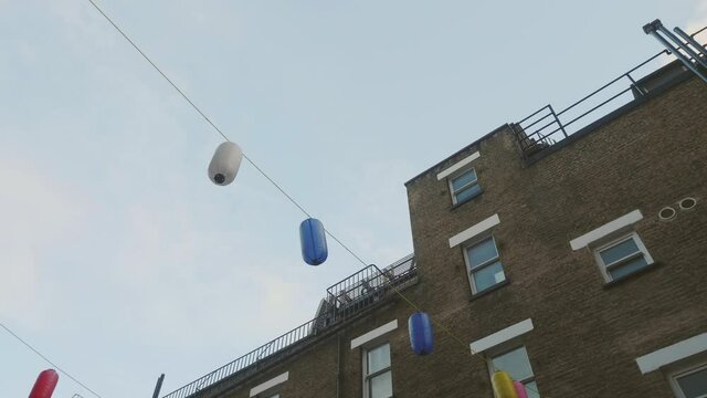 Chinese lamps dangling in the wind between houses in Chinatown, London.