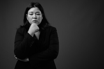 Beautiful overweight Asian businesswoman against gray background