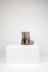 Gray brown suede boots with a shiny insert on a gray background.