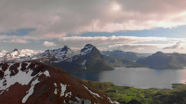 Aerial drone push in of panorama mountain view of Helgeland in northern Norway at golden hour from another mountain top.