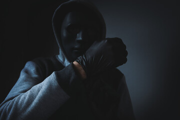 man with hood and face mask puts on black gloves