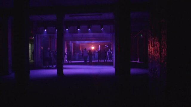 Silhouetted people entering almost empty nightclub with flashing lights