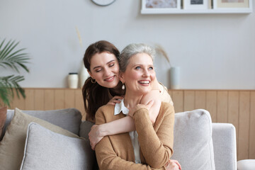 Portrait of old mother and mature daughter hugging at home. Happy senior mom and adult daughter...