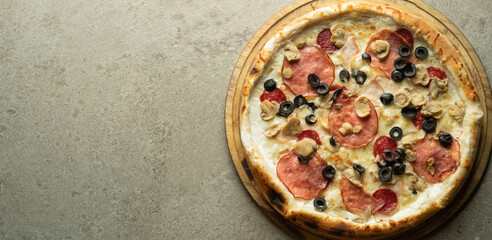 Italian pizza with olives, cheese and sausage on a gray background. Ready-made pastries in a pizzeria.