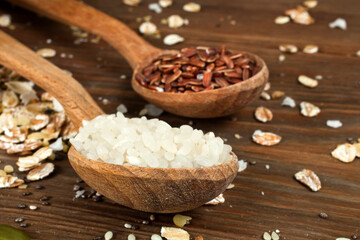 Brown and white rice with oat flakes on a wooden background.  