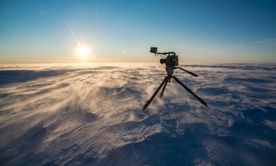 Video camera on tripod in the Antarctic desert at time sunset.