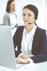 Call center. Beautiful woman sitting and working in headset at customer service office. Business concept
