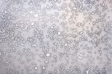 Natural background with white frost on the frozen window glass in the cold winter day front view closeup