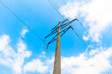 High-voltage transmission line with concrete supports on the background of blue sky