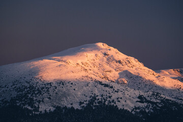 Sunrise light touches mountains peak against clear sky, Guadarrama