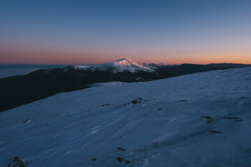 Sunrise first light snowcapped mountains peaks against clear sky