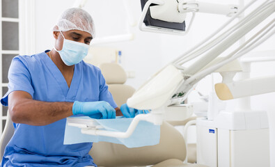 Latin american dentist working at modern dental office, preparing special medical tools