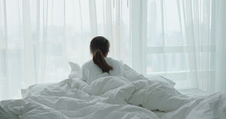 Woman lay down on bed and look outside the window