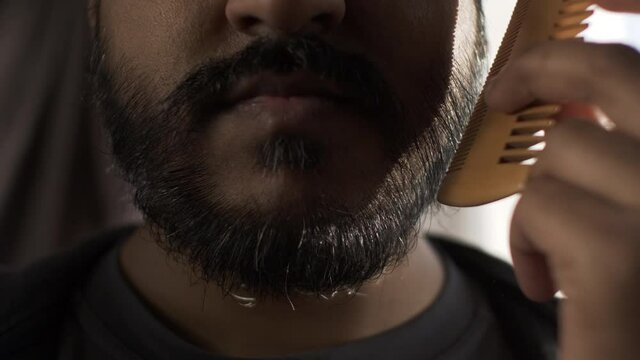 Close Up Of Ethnic Minority Adult Male Combing Beard. Locked Off , Half Face View