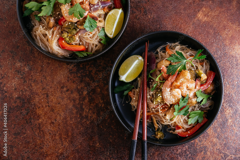 Wall mural stir fried noodles with shrimps and vegetables in a wok on dark