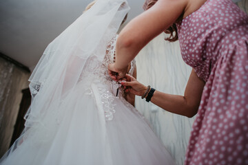 mom ties a bow on the bride's dress