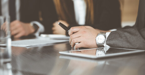 Unknown businessmen and woman sitting, working and discussing questions at meeting in modern office, close-up