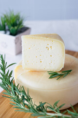 A head with a slice of classic Italian cheese Caciotta made from natural cow's milk on cutting board, selective focus
