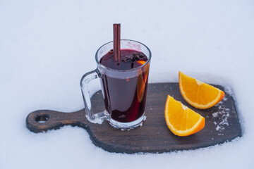 Glass with mulled red wine on a bed of snow and white background, close up. Christmas beverage