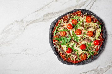 black dough pizza with anchovy arugula, capers