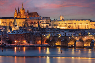 .Charles Bridge on the Vltava River and Prague Castle and the Church of St. Vitus in winter and snow on the roofs in the center of Prague in the early evening