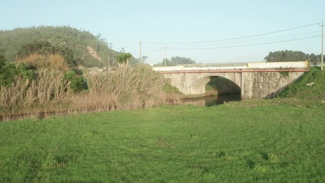 Greenery Landscape By The Calm River Over County Arch Bridge At Alcobaca River Near Nazare, Portugal. - Approach Shot