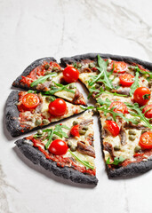 black dough pizza with anchovy arugula, capers