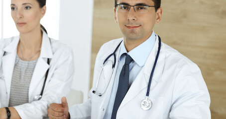 Fototapeta premium Two doctors discussing treatment problems while sitting at the desk in hospital office. Data in medicine and health care concept