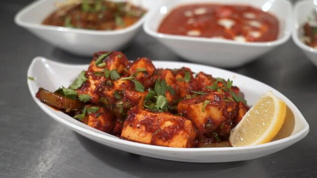 A traditional paneer tikka masala served in Indian restaurant, close up slow motion orbit 4K