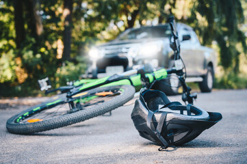 Close-up of a bicycling helmet fallen on the asphalt next to a bicycle after car accident on the...