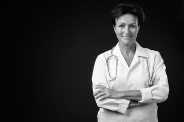 Mature beautiful woman doctor with short hair against black background