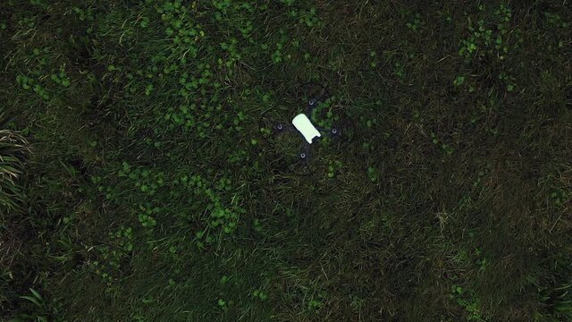 Vertical Top Down View of Drone Hovering Above Green Field.