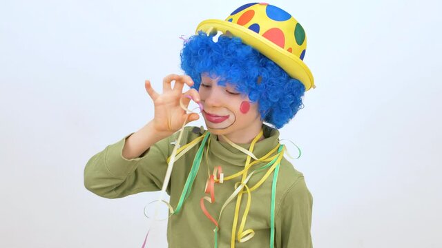 little boy with wig and clown nose has fun with confetti and streamers celebrating carnival