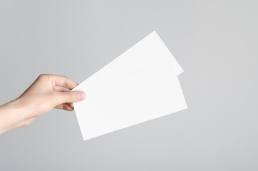 DL Flyer Mock-Up - Male hands holding blank flyers on a gray background.