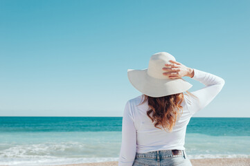 Fototapeta na wymiar Woman wearing a hat looking at the sea