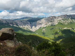Naklejka premium View of Gola Su Gorropu gorge, famous hiking destinantion at green forest landscape of Supramonte Mountains with limestone rock and mediterranean vegetation, Nuoro, Sardinia, Italy. Summer cloudy day