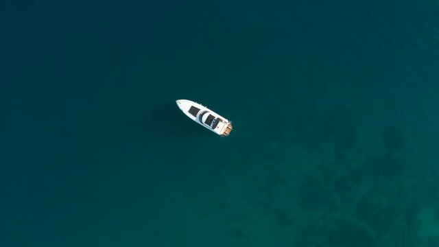 An aerial scene from a birds eye view shows an expensive yacht floating in tropical waters.
