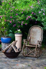 Fototapeta na wymiar rocking chair and fire pit on garden patio with flowers