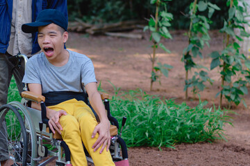 Asian special child on wheelchair and teacher happy on vegetable garden background,Activity in outdoor classroom with school, Life in the education age of disabled children,Happy disabled kid concept.