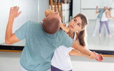 Fotobehang Young woman practicing elbow blow with male partner during self defense course in gym.. © JackF