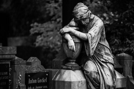 sad statue in cemetary in black and white