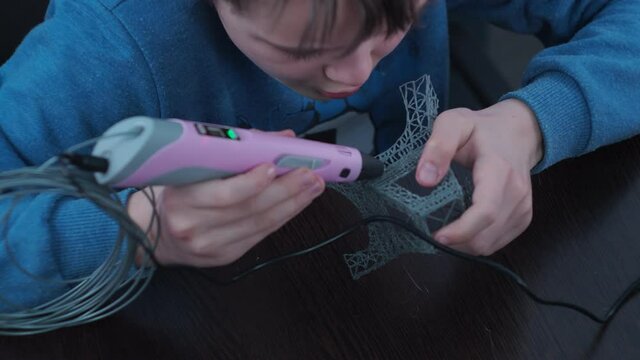 a boy makes a 3 d model with a pen. assembling the layout of the elfin tower.