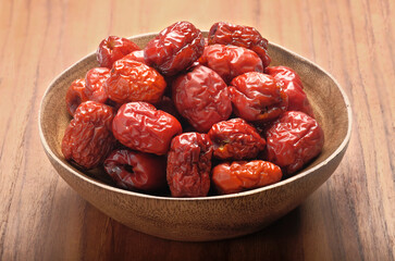 Dried red dates or dried jujube in wooden bowl on wood table.