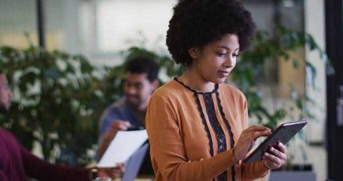 Diverse business people sitting using laptops going through paperwork in office