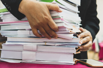 Teacher arranging stacks of lot documents report papers waiting be managed on desk in busy office....