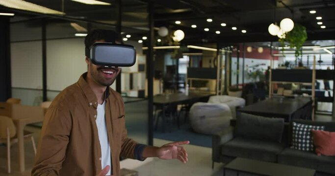 Mixed race businessman standing anfd using vr googles in a modern office