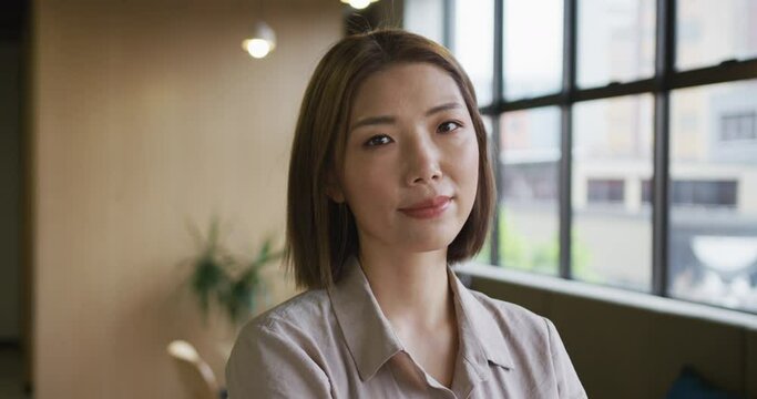 Asian businesswoman standing looking out of window in modern office