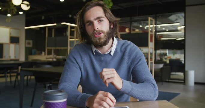 Caucasian businesswman having a video chat going through paperwork in modern office