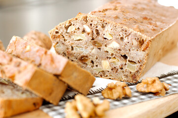 Homemade biological cake with walnuts, apple and raisins, cut open on a wooden tray.  Homemade bakery for healthy living concept with selective focus.
